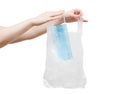 Woman is putting used disposal nonwoven safety mask in plastic bag before throwing it away. Royalty Free Stock Photo