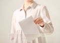 Woman putting vote into ballot box against light background