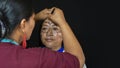 Woman of the Quichua ethnic group of the Ecuadorian Amazon applying makeup to her sister`s face in traditional dress on a black