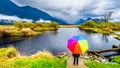 Woman with a rainbow colored Umbrella under dark rain clouds on a cold spring day at the lagoons of Pitt-Addington Marsh Royalty Free Stock Photo