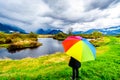 Woman with a rainbow colored Umbrella under dark rain clouds on a cold spring day at the lagoons of Pitt-Addington Marsh Royalty Free Stock Photo