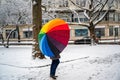 Woman with rainbow umbrella walking down snow-covered street Royalty Free Stock Photo