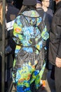 Woman with raincoat with black, blue, green and orange pixel design before Daks fashion show, Milan Fashion