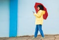 Woman, raincoat and phone typing with umbrella on city street for social media, internet or urban communication. Smile