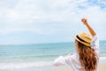 Woman raise hand up on the beach. Happy woman wearing hat