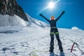 Woman raised her arms and greeting bright sun and blue sky while ascending Mont Blanc Monte Bianco summit dressed mountaineering Royalty Free Stock Photo