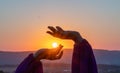 Woman raises arms in lavander field at sunset enjoys sunset in purple flower field. Serene floral setting. Setting sun