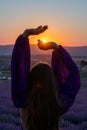 Woman raises arms in lavander field at sunset enjoys sunset in purple flower field. Serene floral setting. Setting sun Royalty Free Stock Photo