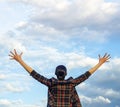 A young woman stretches her arms up against the sky while standing with her back. Royalty Free Stock Photo