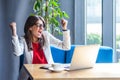 Woman raising hands celebrating successful business online, rejoicing victory, working on laptop. Royalty Free Stock Photo