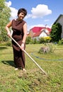 Woman rakes up oblique grass