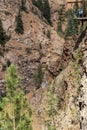 Woman rappelling down a steep and tall mountain cliff in the Rockies with a group of people waiting on a platform for their turn