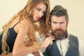 Woman with razor, scissors cut hair of man. Bearded man and sexy woman with long curly hair. Couple make haircut Royalty Free Stock Photo