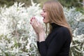 Woman with hay fever in front of white flowers