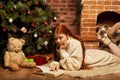 Woman reading book on Christmas in front of tree