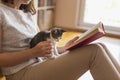 Woman reading book and cuddling kitten Royalty Free Stock Photo