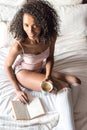 Woman reading a book and drinking coffee on bed with socks Royalty Free Stock Photo