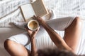 Woman reading a book and drinking coffee on bed with socks Royalty Free Stock Photo