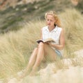 Woman reading book, enjoying sun on beach. Royalty Free Stock Photo