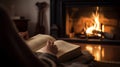 Woman reading a book in front of a fireplace at home in the evening