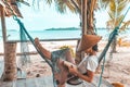 Woman reading book on hammock tropical beach, real people getting away from it all, traditional south asian hat, palm trees, teal Royalty Free Stock Photo