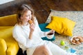 Woman reading book at home and sitting on the floor next to yellow armchair Royalty Free Stock Photo