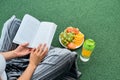 Woman reading book on the lawn, top view over shoulder Royalty Free Stock Photo