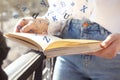 Woman reading book with letters flying over it outdoors on sunny day, closeup Royalty Free Stock Photo