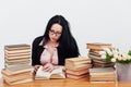 a woman reading a book in a library near a stack of books Royalty Free Stock Photo