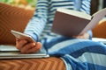 Woman reading book and looking at smartphone Royalty Free Stock Photo