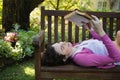 Woman reading a book while lying on a bench Royalty Free Stock Photo