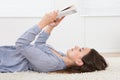 Woman Reading Book While Lying On Rug At Home Royalty Free Stock Photo