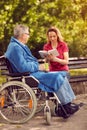 Woman reading book outdoor her disabled father in wheelchair Royalty Free Stock Photo