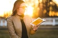 Woman reading book outside in park. Lady enjoying novel outdoors