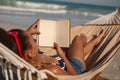 Woman reading a book while relaxing on hammock on beach Royalty Free Stock Photo