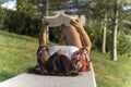 Woman reading a book while relaxing lying on a bench in a park Royalty Free Stock Photo