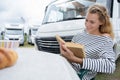 woman reading book sat by campervan Royalty Free Stock Photo