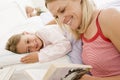 Woman reading book to young girl in bed smiling Royalty Free Stock Photo