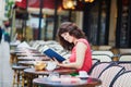 Woman reading a book in traditional Parisian outdoor cafe, Paris, France Royalty Free Stock Photo