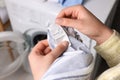 Woman reading clothing label with care symbols and material content on shirt near washing machine, closeup