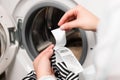 Woman reading clothing label with care symbols and material content on striped shirt near washing machine, closeup