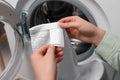 Woman reading clothing label with care symbols and material content on white towel near washing machine, closeup