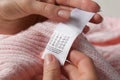 Woman reading clothing label with care symbols on knitted sweater, closeup Royalty Free Stock Photo