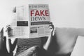 Woman reading coronavirus fake news from a newspaper during coronavirus quarantine Royalty Free Stock Photo