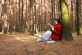 Woman reading an ebook or tablet in an urban park, sit under tree Royalty Free Stock Photo