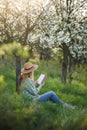 Woman is reading in her notebook diary and relaxing under blooming cherry tree Royalty Free Stock Photo