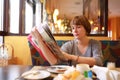 Woman reading magazine at breakfast Royalty Free Stock Photo