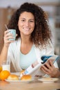 woman reading magazine while eating breakfast in kitchen at home Royalty Free Stock Photo