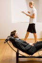 Woman reading man lying on chaise longue Royalty Free Stock Photo