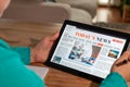 Woman reading the news on a tablet at home. Imaginary online, mobile website, application or news portal on modern touch screen. Royalty Free Stock Photo
